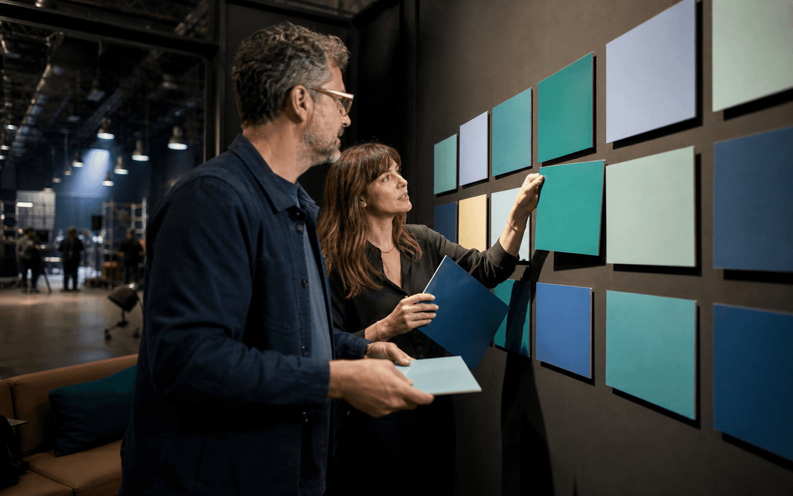 Producer and executive arranging solid-color cards on a studio planning wall